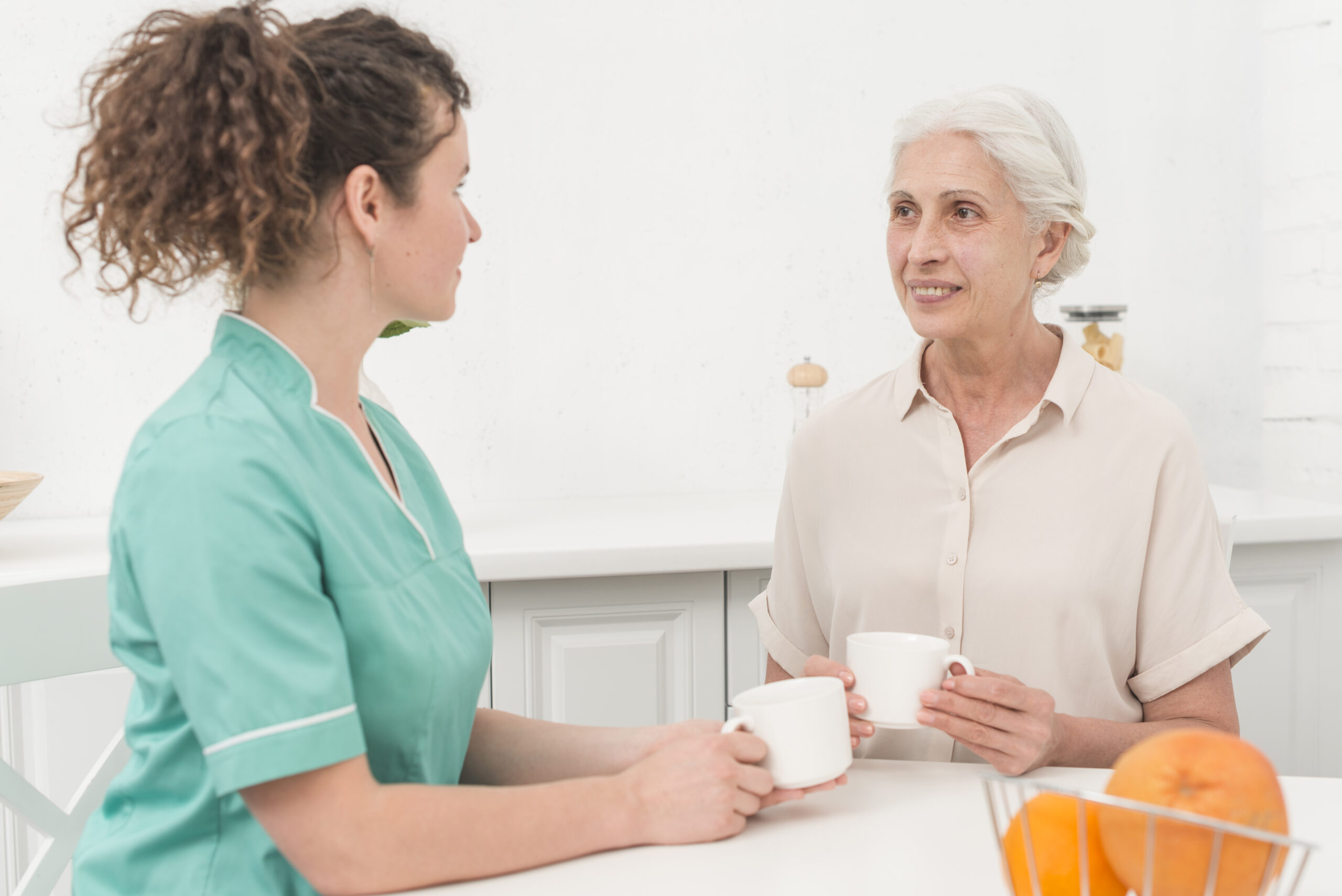 female nurse drinking coffee with senior woman